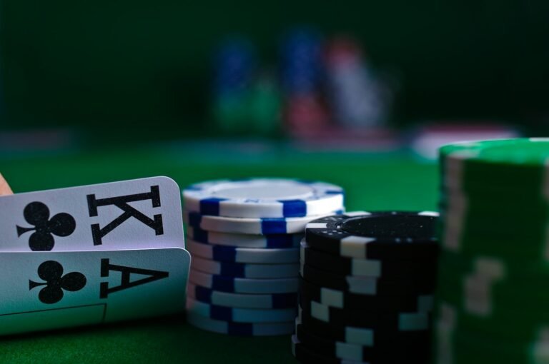 A hand holding playing cards beside stacks of poker chips